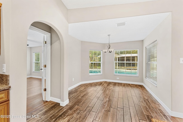 unfurnished dining area featuring dark hardwood / wood-style flooring and a notable chandelier