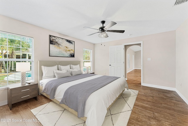 bedroom with wood-type flooring, multiple windows, and a textured ceiling