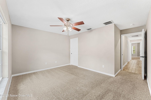 carpeted spare room featuring ceiling fan and a textured ceiling