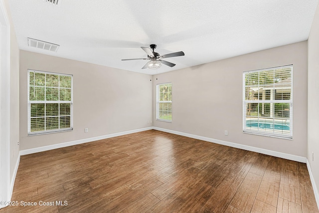 empty room with ceiling fan, wood-type flooring, and a textured ceiling