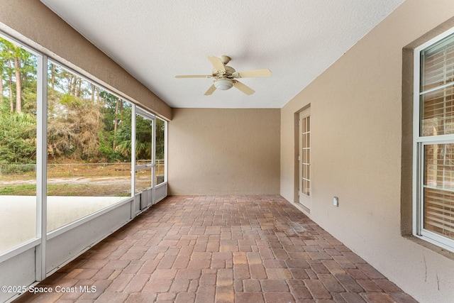 unfurnished sunroom with ceiling fan