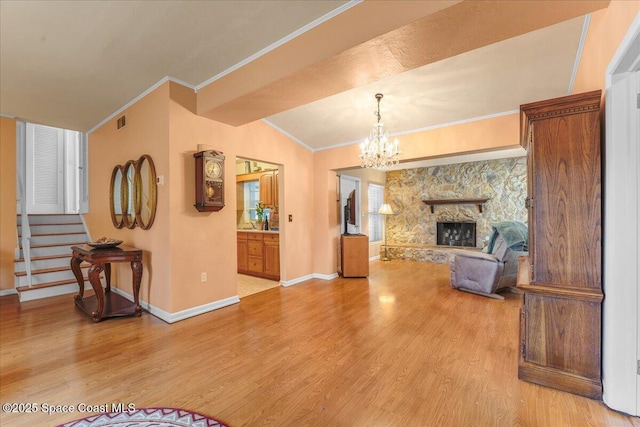 living room featuring a stone fireplace, ornamental molding, a chandelier, and light wood-type flooring