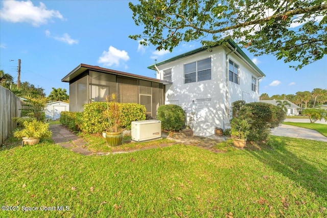 rear view of house featuring a yard and a sunroom