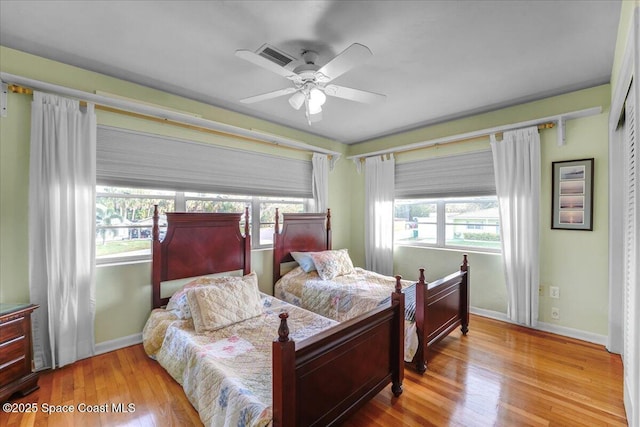 bedroom featuring multiple windows, ceiling fan, and light wood-type flooring