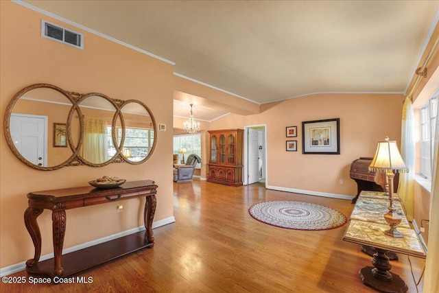 entrance foyer featuring crown molding, hardwood / wood-style flooring, vaulted ceiling, and a healthy amount of sunlight