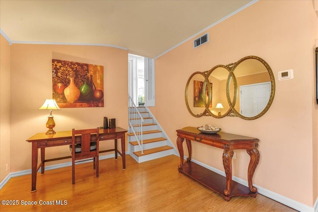 interior space featuring wood-type flooring, vaulted ceiling, and crown molding