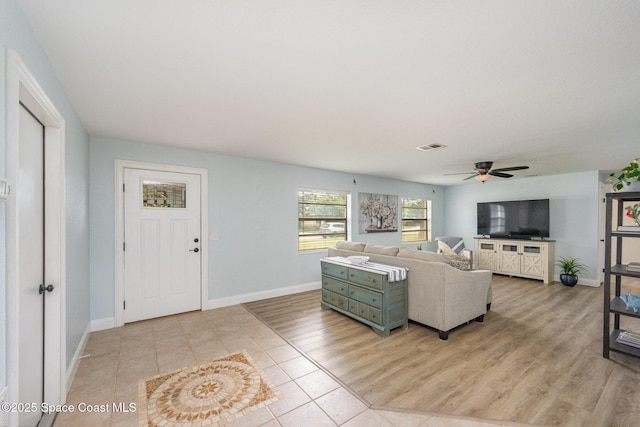 living room featuring a ceiling fan, light wood-type flooring, visible vents, and baseboards