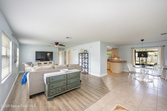 living area featuring light wood finished floors, a ceiling fan, visible vents, and baseboards