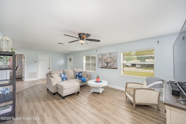 living room featuring visible vents, light wood-style flooring, and baseboards