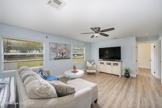 living room featuring light wood finished floors, a ceiling fan, visible vents, and baseboards