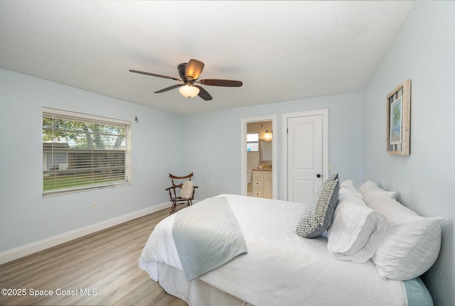 bedroom with a textured ceiling, connected bathroom, a ceiling fan, baseboards, and light wood-type flooring