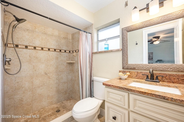 bathroom featuring toilet, tiled shower, and vanity