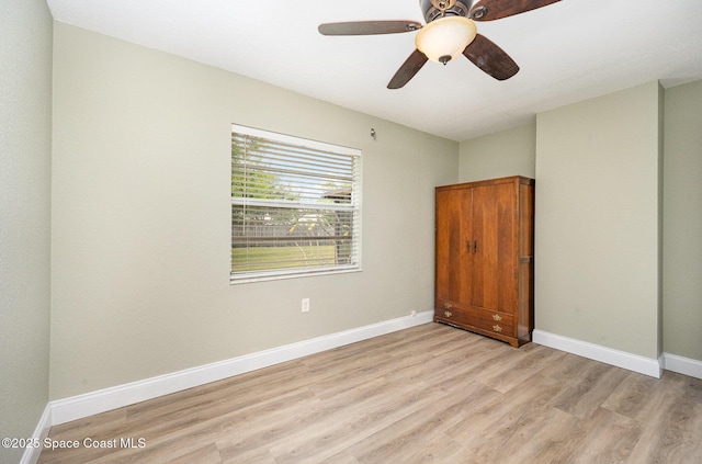 spare room featuring light wood-style floors, baseboards, and a ceiling fan