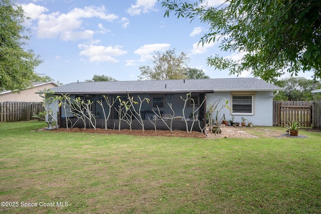 rear view of house with a sunroom, fence, and a yard