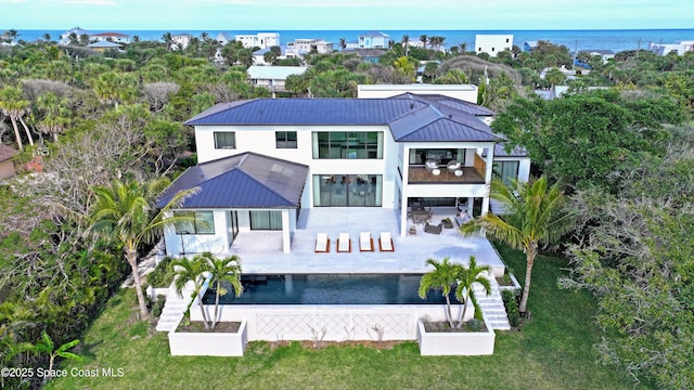 rear view of property featuring a patio, a balcony, and a water view