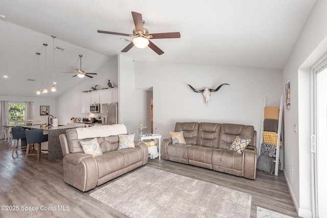 living room with vaulted ceiling, ceiling fan, and light hardwood / wood-style floors