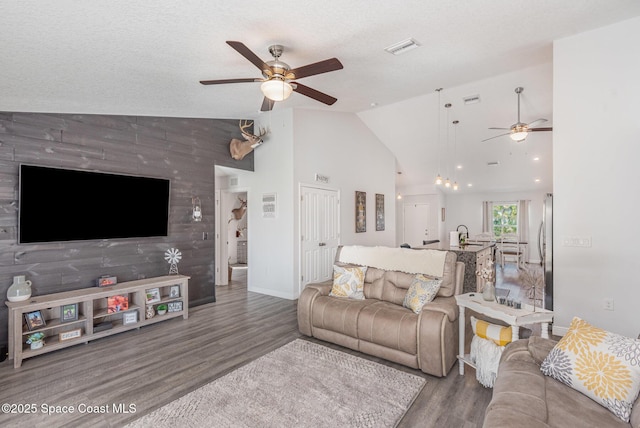 living room featuring sink, hardwood / wood-style flooring, ceiling fan, a textured ceiling, and vaulted ceiling