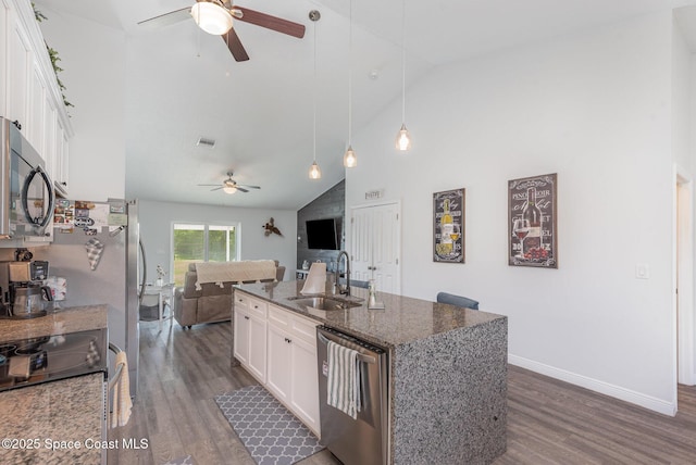 kitchen with sink, white cabinetry, dark stone counters, stainless steel appliances, and a kitchen island with sink