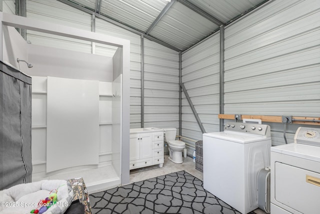 bathroom featuring vaulted ceiling, washing machine and dryer, concrete floors, and toilet