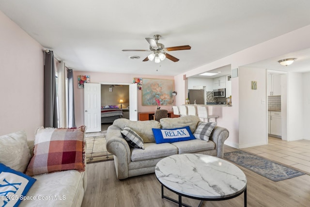 living room with light hardwood / wood-style flooring and ceiling fan