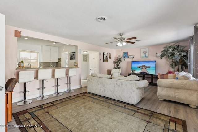 living room with sink, wood-type flooring, and ceiling fan