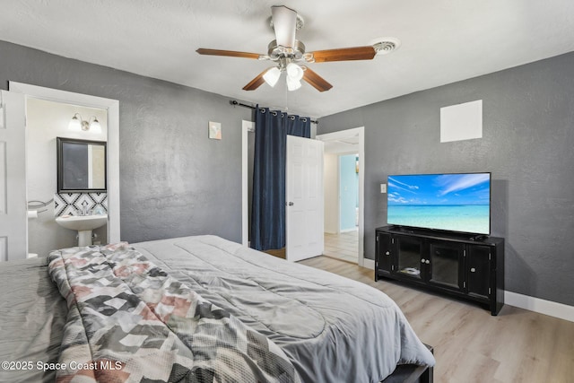 bedroom featuring a barn door, ceiling fan, and light wood-type flooring