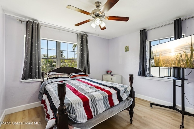 bedroom with ceiling fan, multiple windows, and light wood-type flooring