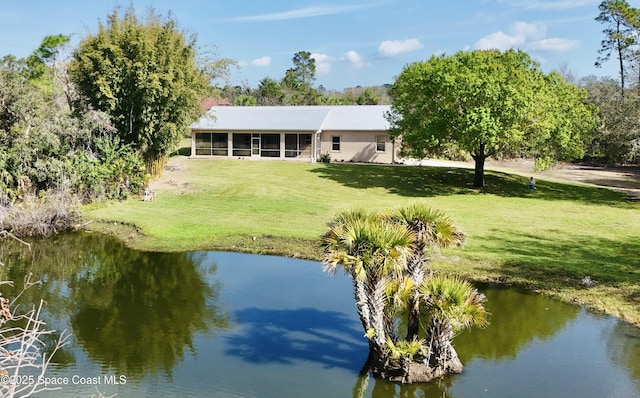 back of house featuring a water view, a yard, and a sunroom