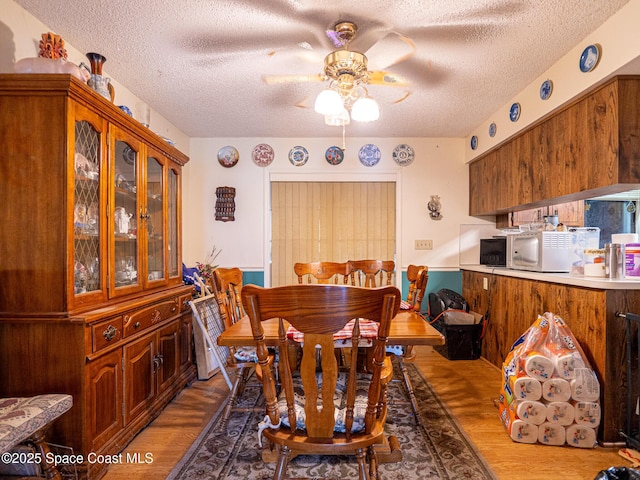 dining area with ceiling fan, hardwood / wood-style flooring, and a textured ceiling