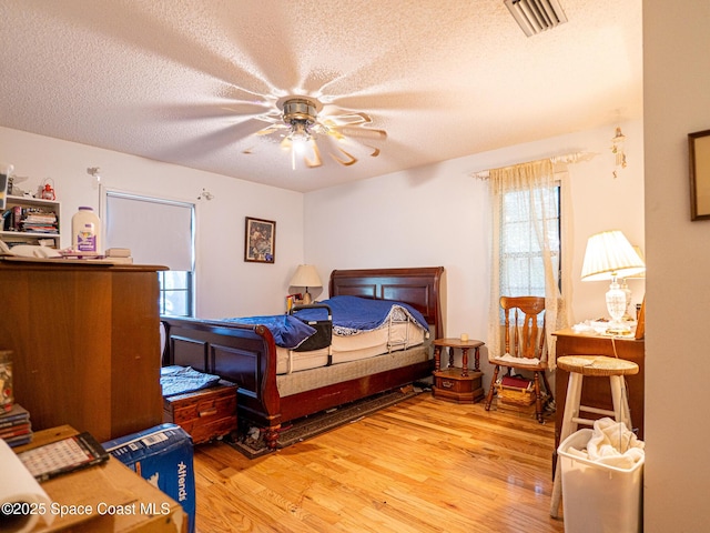 bedroom with ceiling fan, light hardwood / wood-style floors, and a textured ceiling