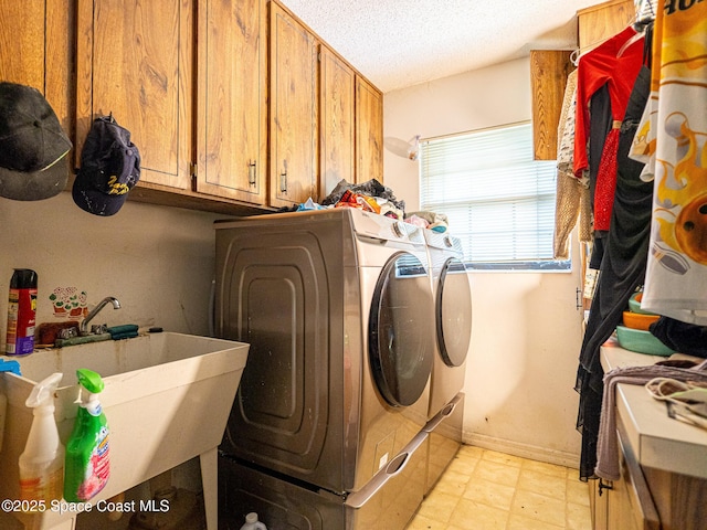 laundry area featuring cabinets, washer and dryer, sink, and a textured ceiling