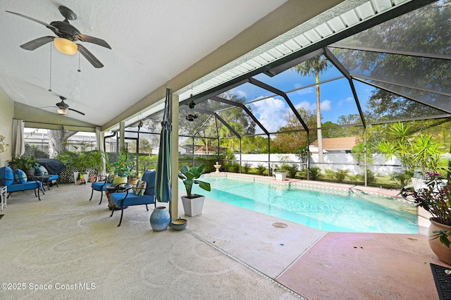 view of pool with ceiling fan, glass enclosure, and a patio area