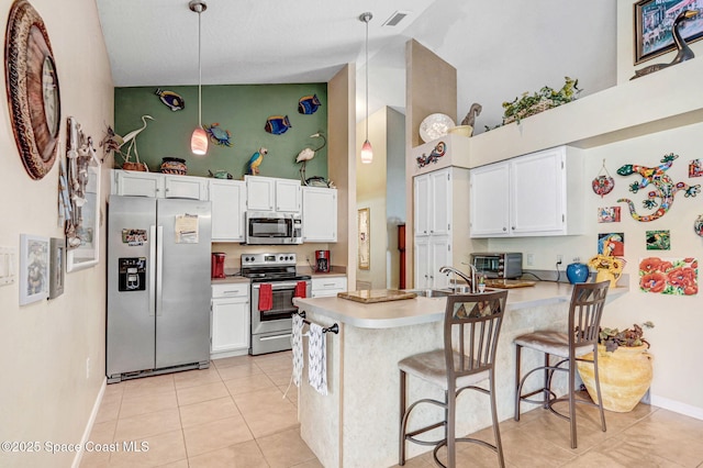 kitchen featuring white cabinetry, decorative light fixtures, appliances with stainless steel finishes, a kitchen breakfast bar, and kitchen peninsula