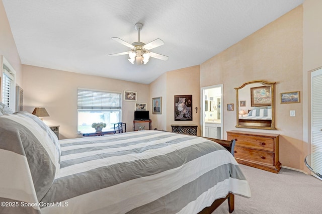 bedroom featuring ceiling fan, light colored carpet, ensuite bathroom, and vaulted ceiling