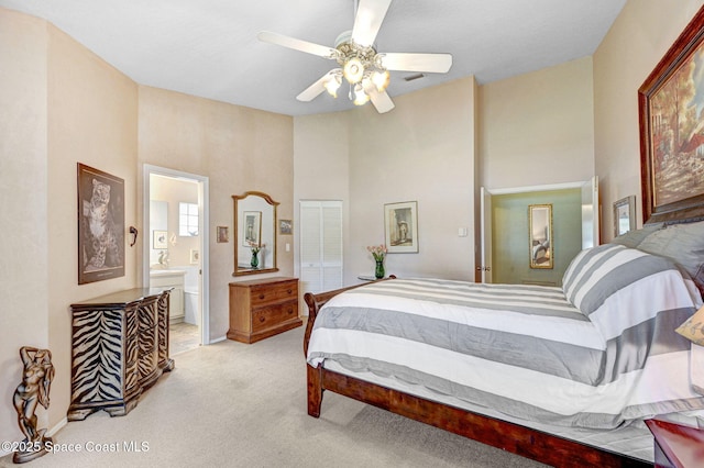 carpeted bedroom featuring a high ceiling, ensuite bathroom, ceiling fan, and a closet