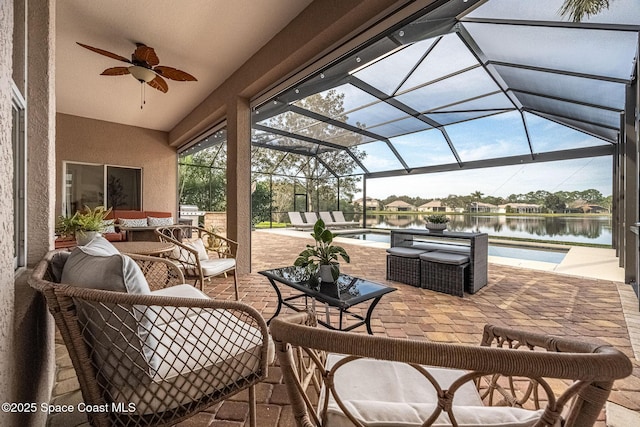 view of patio / terrace with a water view, ceiling fan, an outdoor hangout area, and a lanai