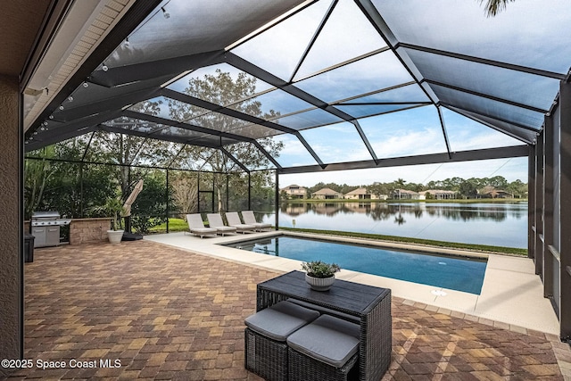 view of swimming pool with a lanai, exterior kitchen, a patio, and a water view