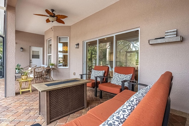 view of patio with a lanai, an outdoor living space with a fire pit, and ceiling fan