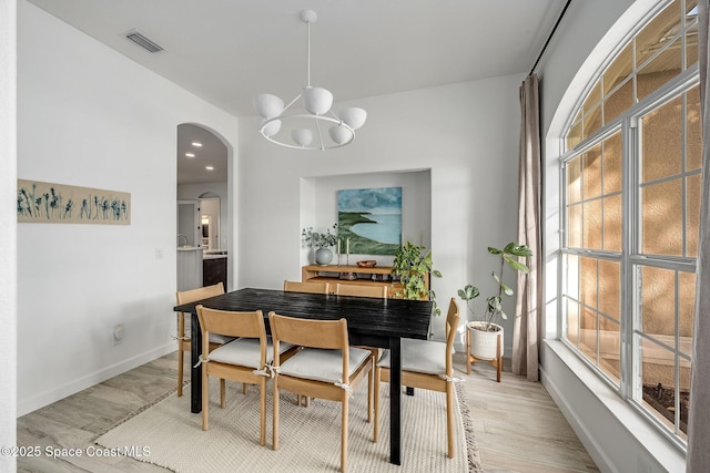 dining space featuring light wood-type flooring and a notable chandelier