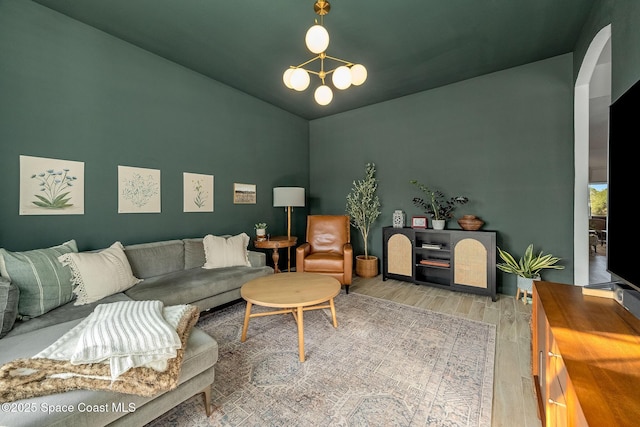 living room with hardwood / wood-style flooring, lofted ceiling, and a chandelier