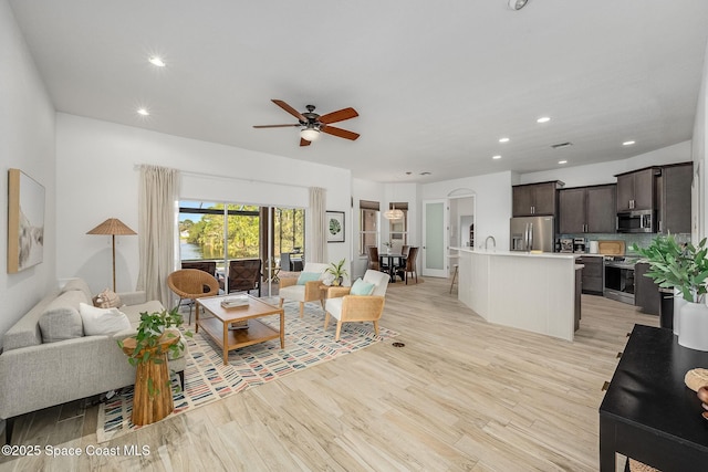 living room featuring sink, light hardwood / wood-style floors, and ceiling fan