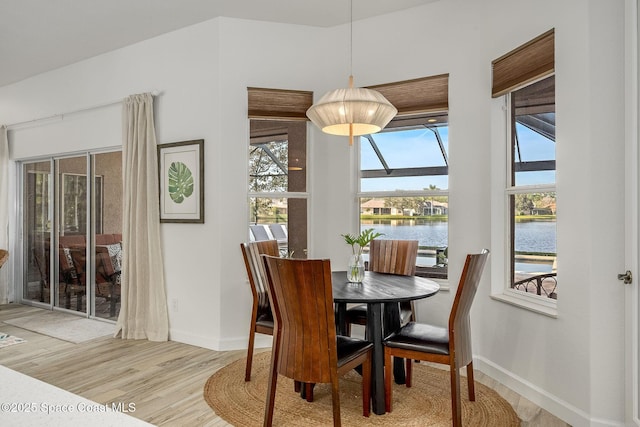 dining area with a water view and light hardwood / wood-style floors