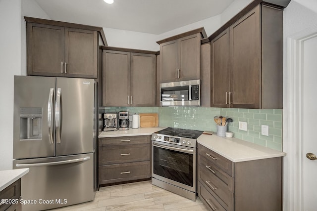 kitchen featuring dark brown cabinetry, backsplash, light hardwood / wood-style flooring, and appliances with stainless steel finishes