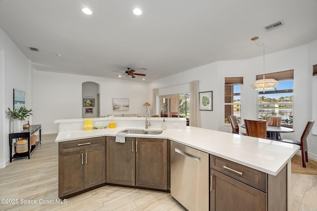 kitchen featuring dishwasher, sink, hanging light fixtures, and light wood-type flooring