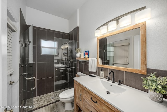 bathroom with toilet, a shower with shower door, vanity, hardwood / wood-style floors, and decorative backsplash