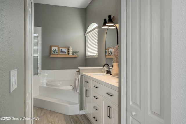 bathroom featuring vanity, wood-type flooring, and tiled bath