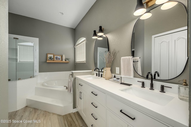 bathroom with vanity, tiled tub, hardwood / wood-style flooring, and lofted ceiling