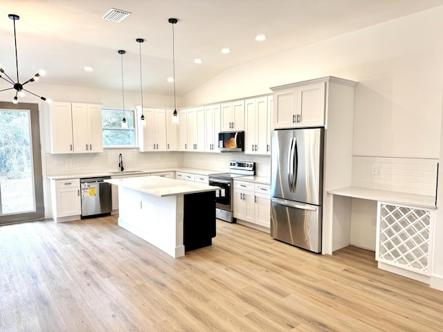 kitchen featuring hanging light fixtures, appliances with stainless steel finishes, sink, and light wood-type flooring