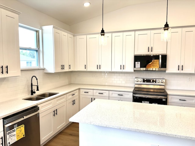 kitchen featuring lofted ceiling, sink, decorative light fixtures, appliances with stainless steel finishes, and white cabinets