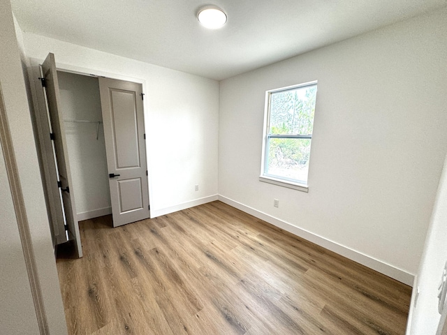 unfurnished bedroom with light wood-type flooring and a closet